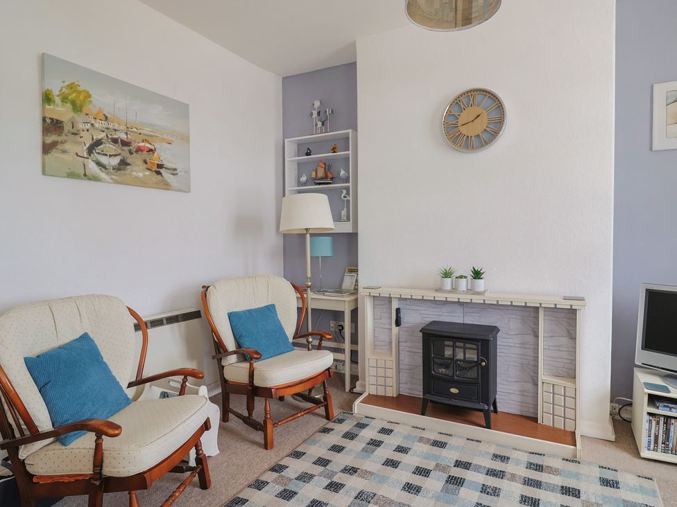A living room with chairs and a television at Flat F