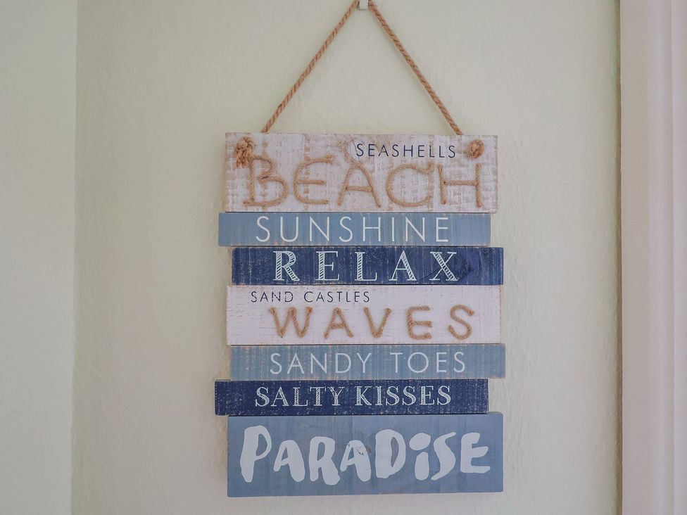 A decorative sign with beach-related phrases at Flat F in 
