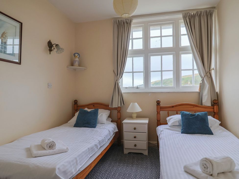 A bedroom with two single beds and a nightstand at Flat F Bay House West Bay
