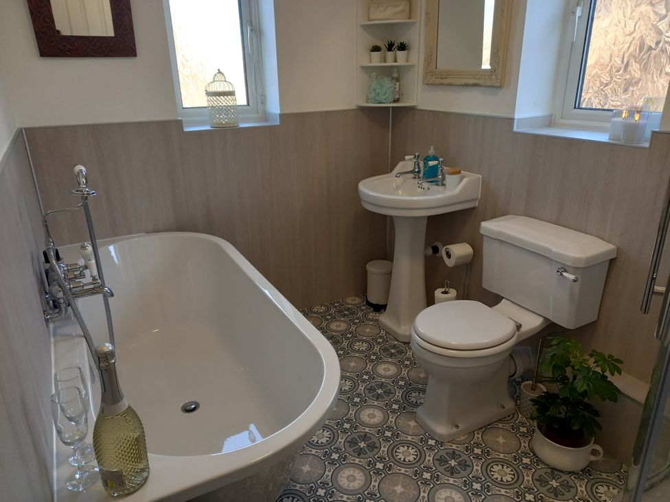 A bathroom with a bathtub, sink, and toilet at Postman's Cottage in Bridlington