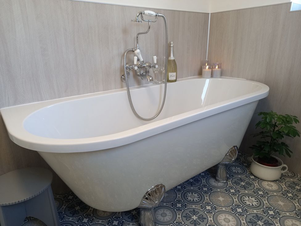 A bathtub with a faucet and candles at Postman's Cottage in Bridlington