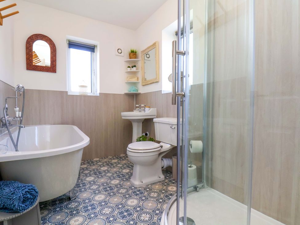 A bathroom with a bathtub, toilet, sink and shower at Postman's Cottage in Bridlington