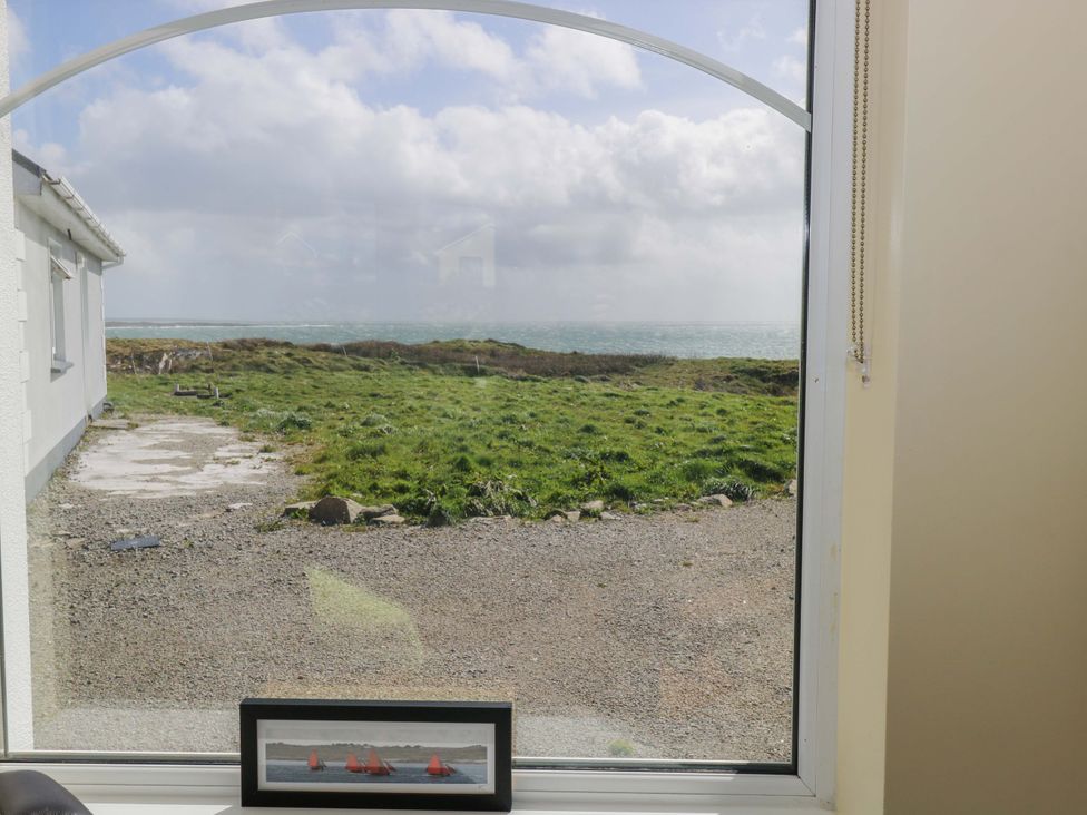 A view through a window showing grass and sea at Tí Tom Nárta, Trabane near Lettermore, County Galway