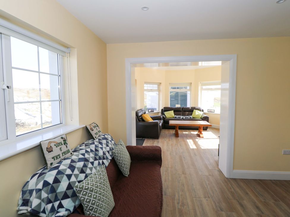A living room with furniture and windows at Tí Tom Nárta in Trabane near Lettermore, County Galway