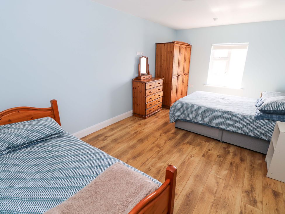 A bedroom with two beds and wooden furniture at Tí Tom Nárta, Trabane near Lettermore, County Galway