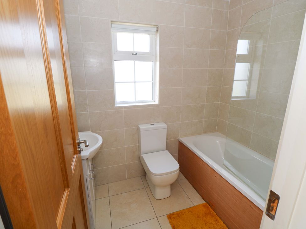 A bathroom with a bathtub, toilet, and sink at Tí Tom Nárta in Trabane near Lettermore, County Galway