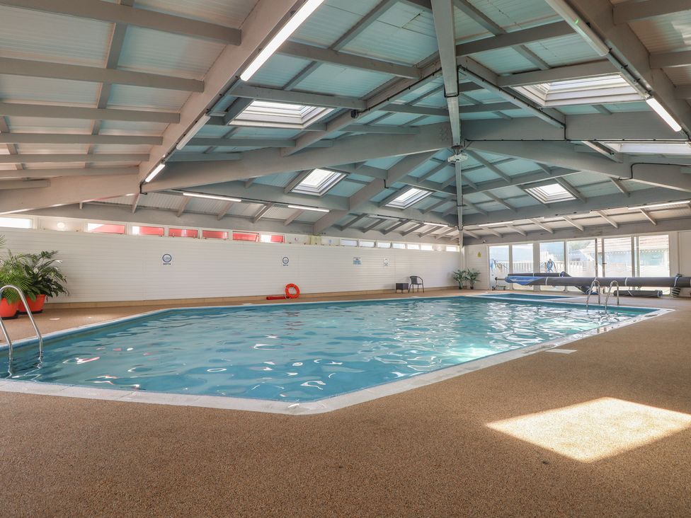 An indoor pool with a ladder and lounge chairs at Lodge 23 in Torpoint