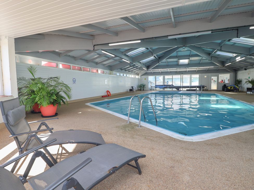 An indoor pool with lounge chairs and a plant at Lodge 23 in Torpoint