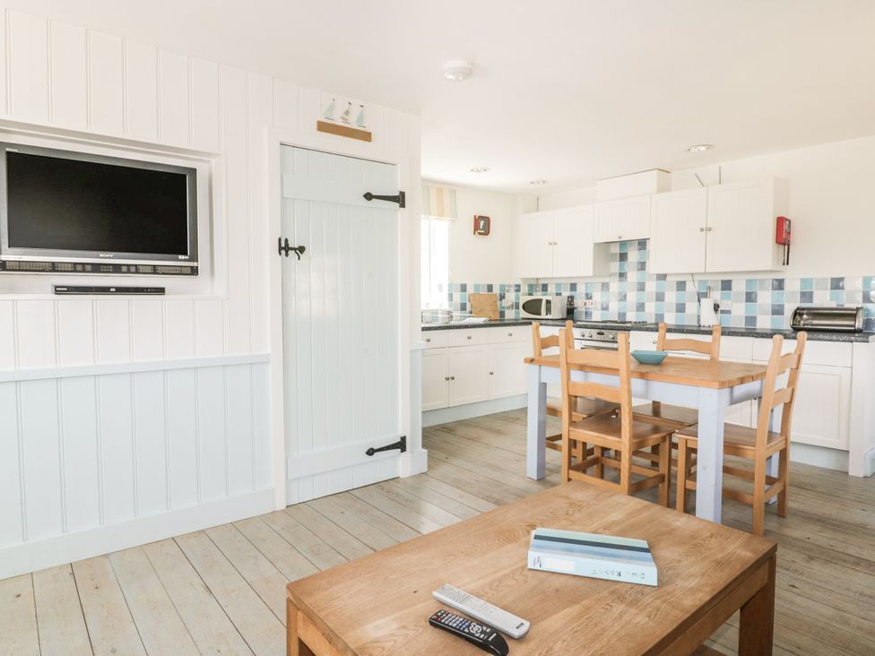 A kitchen with a television, table, and chairs at Owls Roost in Gorran Haven
