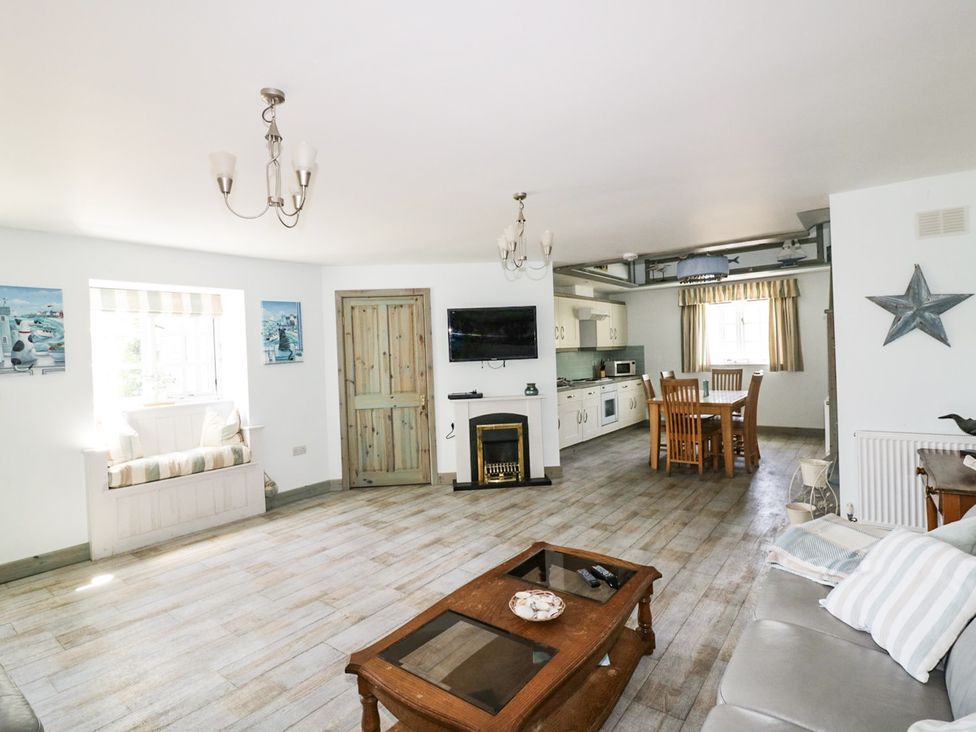 A living room with a sofa and dining area at Squirrels Dray in Gorran Haven