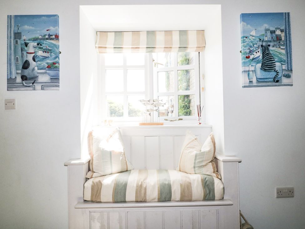 A snug with a window seat and paintings at Squirrels Dray in Gorran Haven