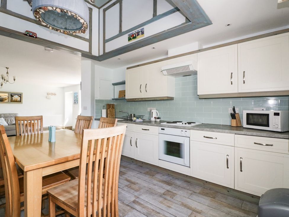 A kitchen with a dining table and appliances at Squirrels Dray in Gorran Haven