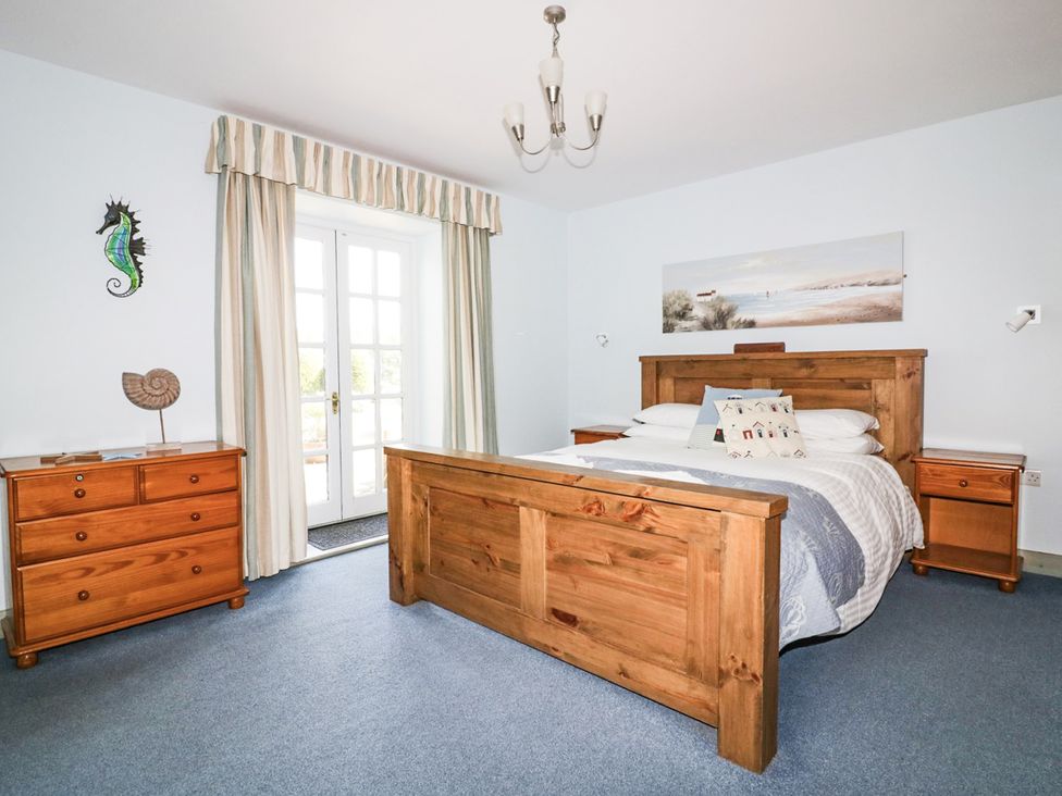 A bedroom with a bed and dressers at Squirrels Dray in Gorran Haven