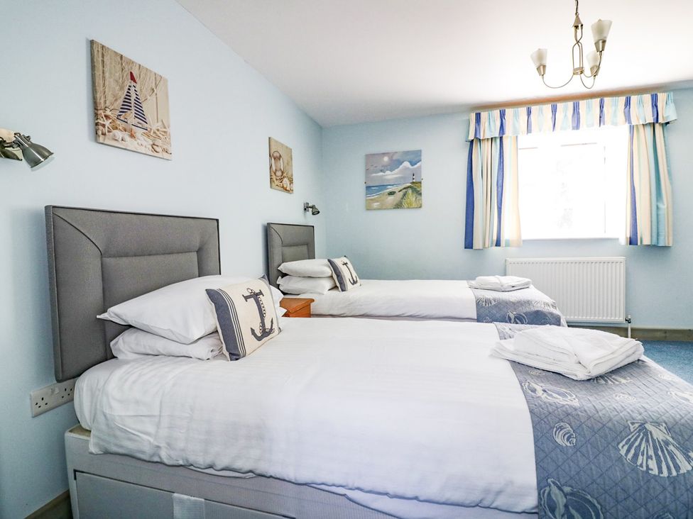 A bedroom with two beds and wall art at Squirrels Dray in Gorran Haven