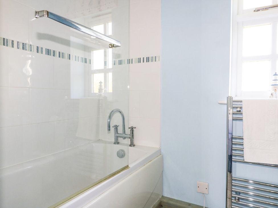 A bathroom with a bathtub and towel radiator at Squirrels Dray in Gorran Haven