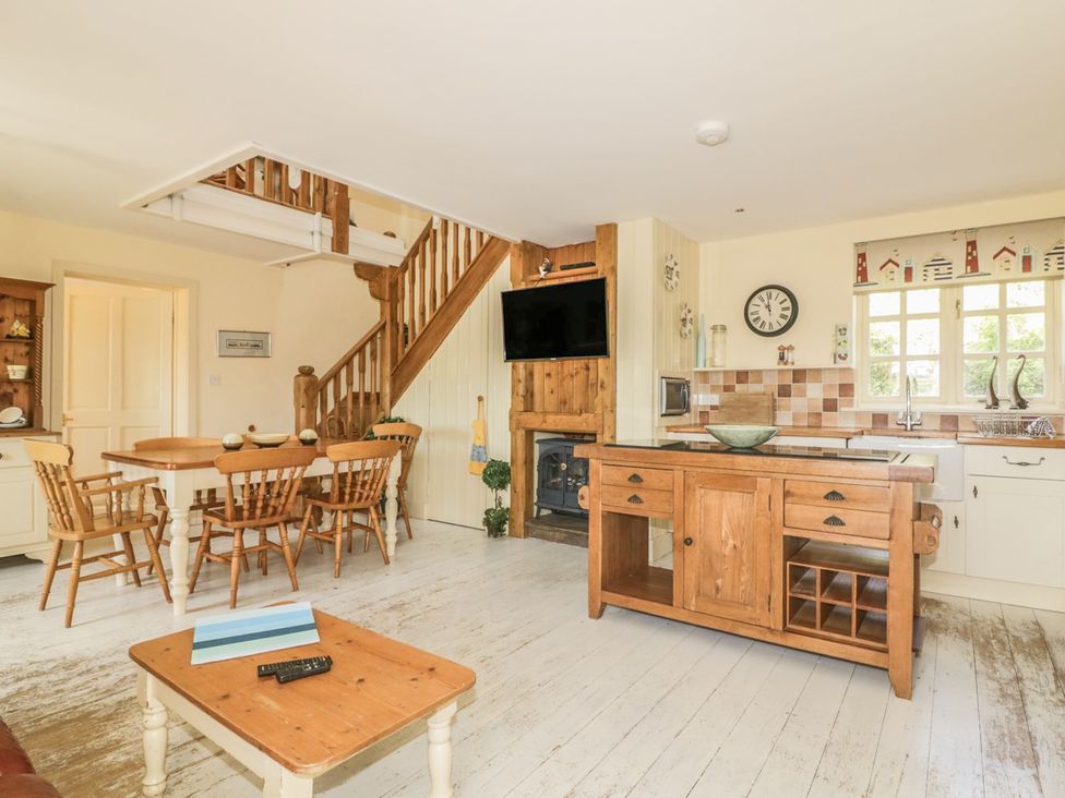 A kitchen with a dining area and wooden furniture at Foxes Den in Gorran Haven