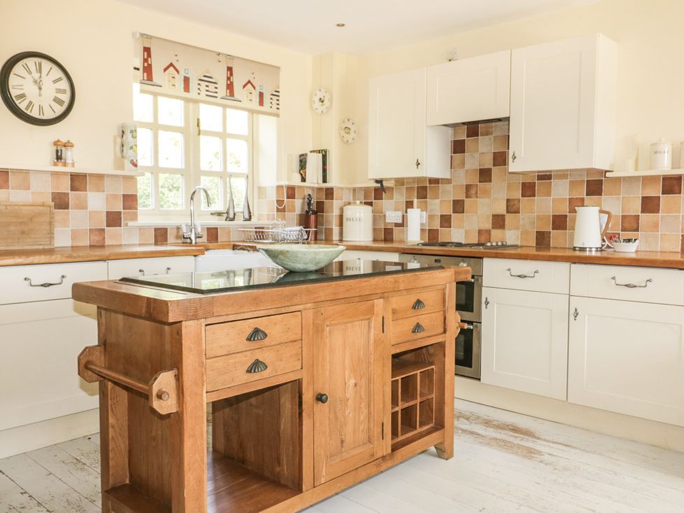 A kitchen with a wooden island and sink at Foxes Den in Gorran Haven