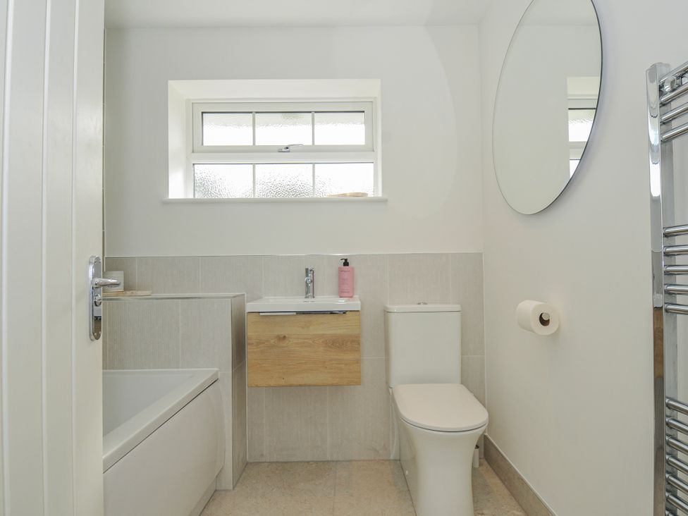 A bathroom featuring a bath tub, toilet, sink and mirror at Samphire in Rock