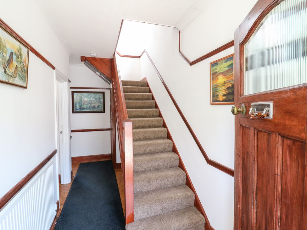 A hallway with a staircase and paintings at Ninety Eight in Southend-On-Sea