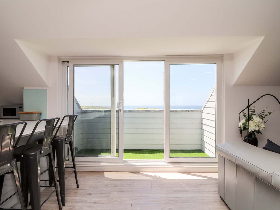 A living room with a balcony and chairs at Penthouse 23 in Newquay
