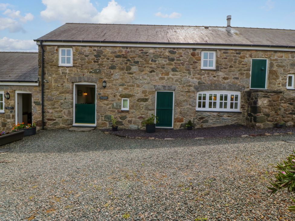 An outdoor view of a stone building with green doors at No 2 The Stables Capel Coch near Llannerch-Y-Medd