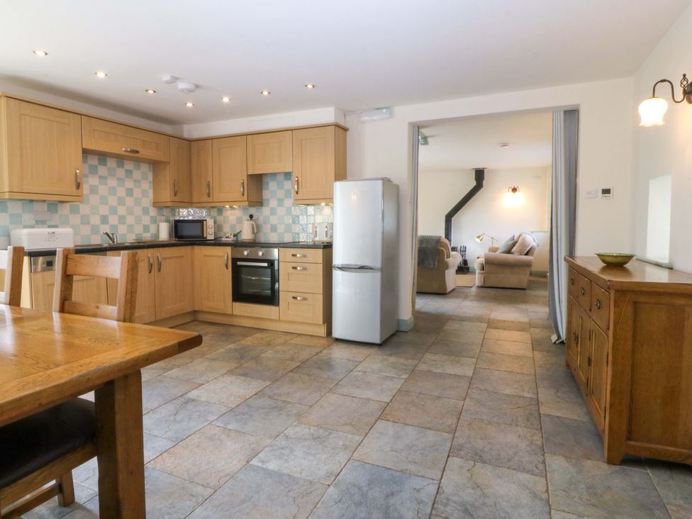 A kitchen with wooden cabinets and a table at No 2 The Stables Capel Coch near Llannerch-Y-Medd