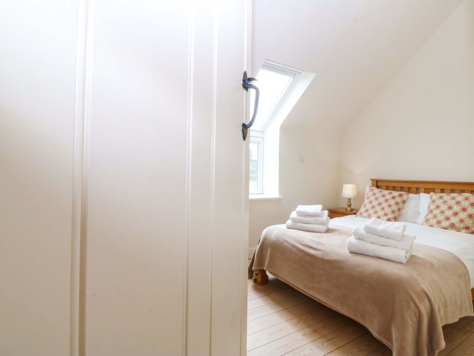 A bedroom with a bed and towels at No 2 The Stables Capel Coch near Llannerch-Y-Medd