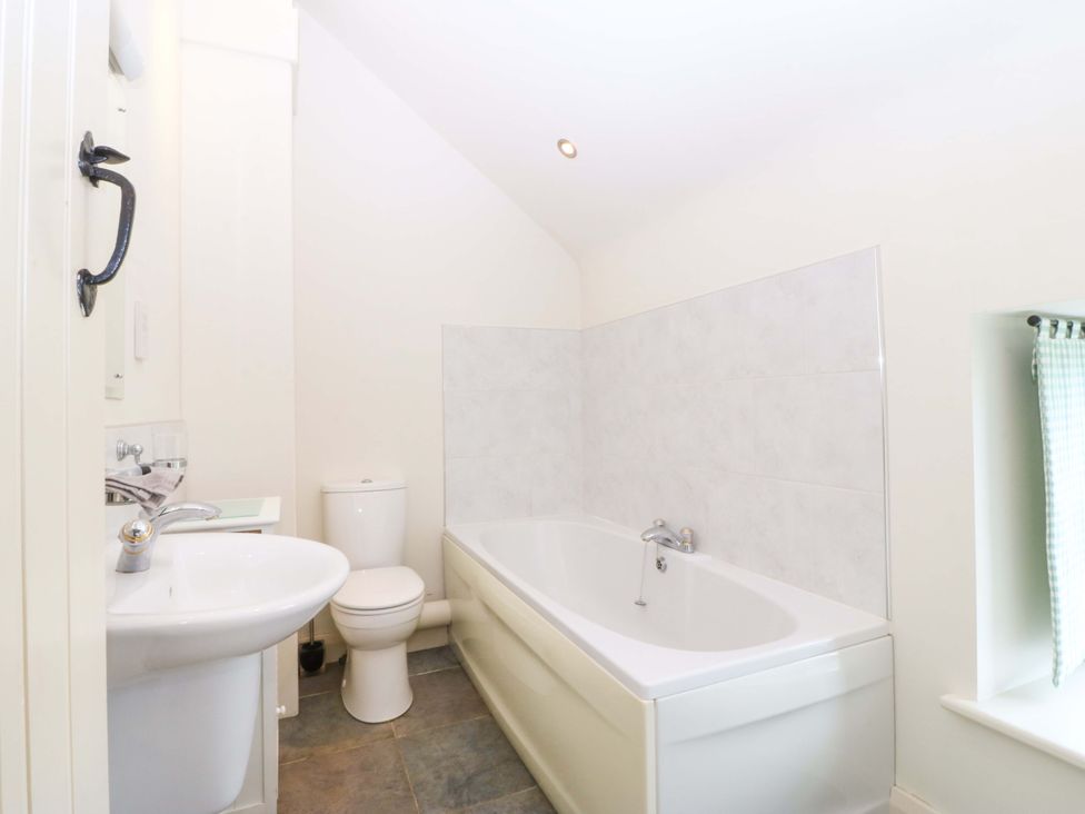 A bathroom with a bathtub, sink, and toilet at No 2 The Stables in Capel Coch near Llannerch-Y-Medd