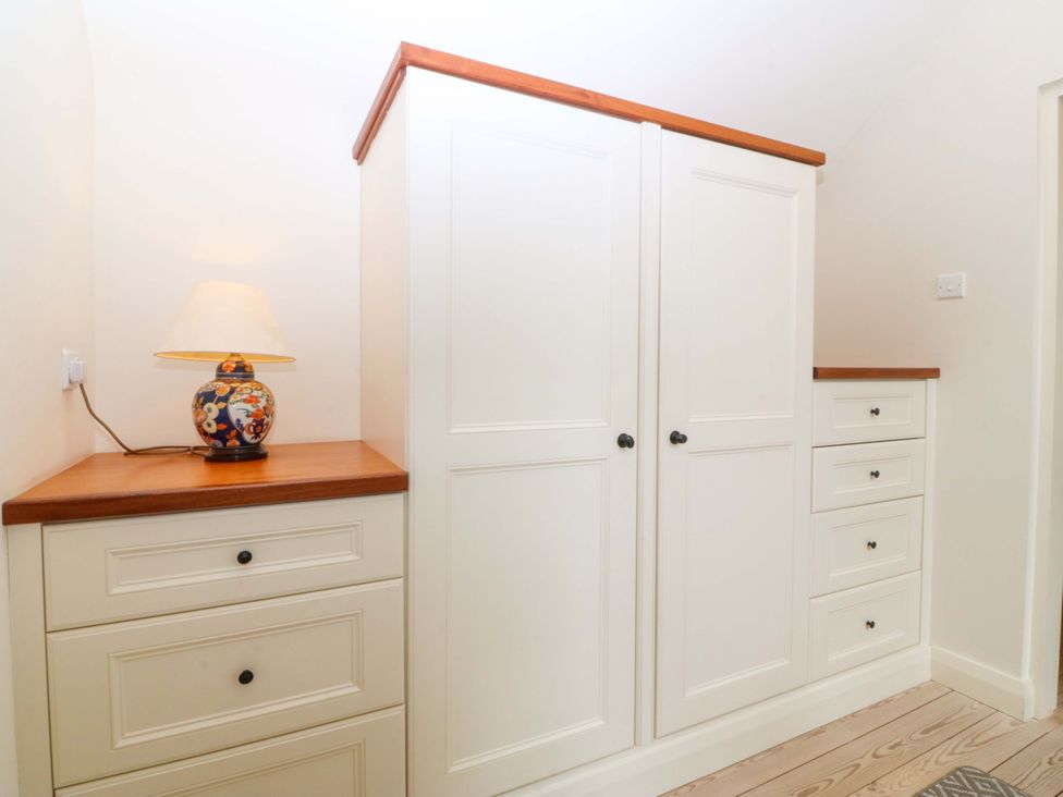 A wardrobe and drawer unit with a lamp in a bedroom at No 2 The Stables Capel Coch near Llannerch-Y-Medd