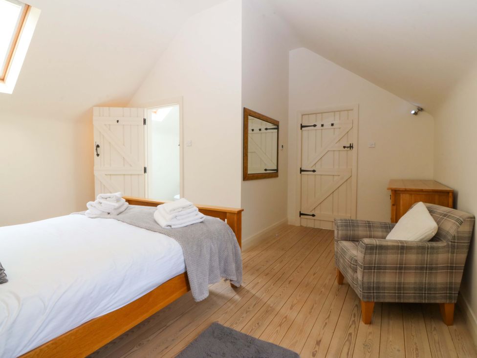 A bedroom with a bed and chair at No 2 The Stables Capel Coch near Llannerch-Y-Medd