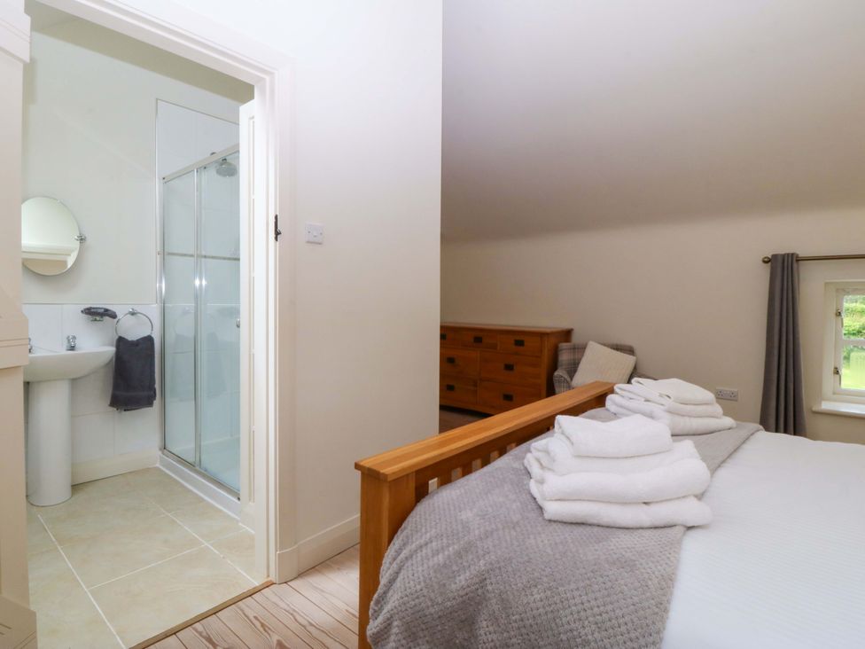 A bedroom with a bed and an attached bathroom at No 2 The Stables Capel Coch near Llannerch-Y-Medd