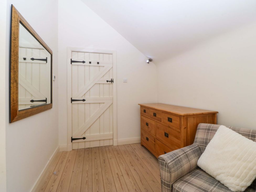 A room with a mirror, chest of drawers, and a sofa at No 2 The Stables in Capel Coch near Llannerch-Y-Medd