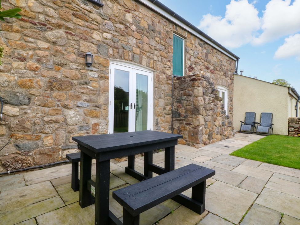 An outdoor patio area with a table and chairs at No 2 The Stables Capel Coch near Llannerch-Y-Medd