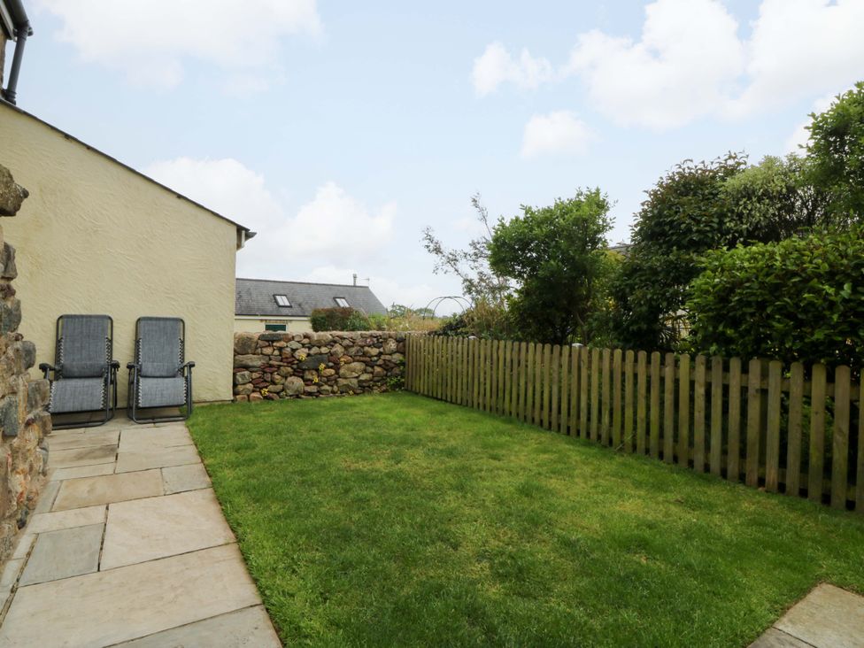 A garden with deck chairs and a stone wall at No 2 The Stables Capel Coch near Llannerch-Y-Medd