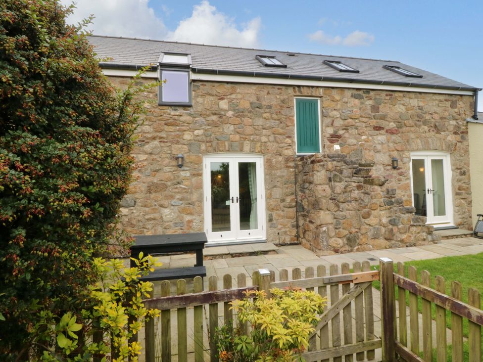 A stone building with windows and doors in an outdoor area at No 2 The Stables Capel Coch near Llannerch-Y-Medd