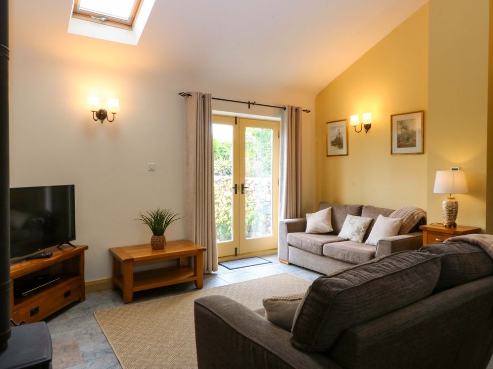 A living room with a sofa and a television at No 3 The Dairy Capel Coch near Llannerch-Y-Medd