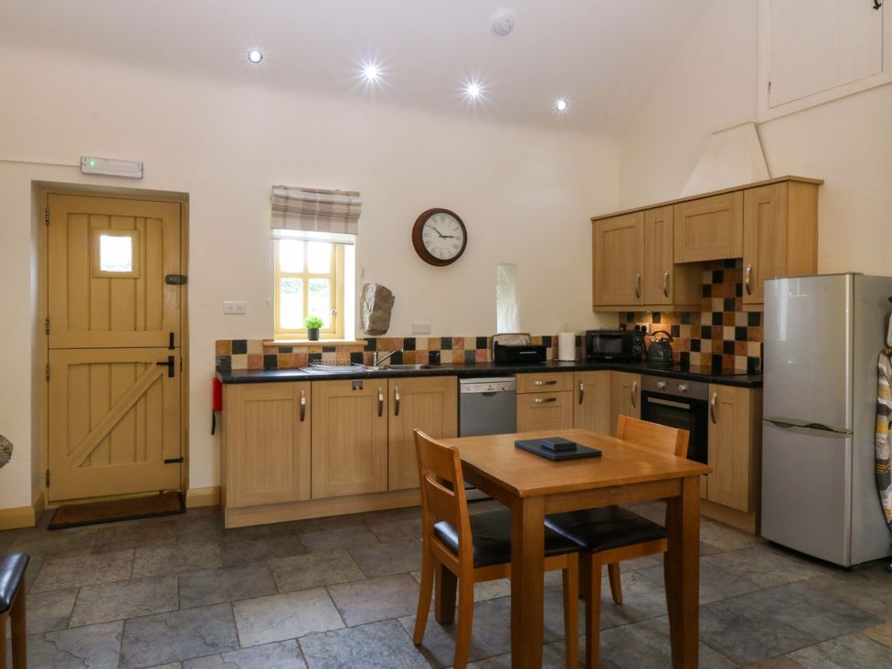 A kitchen with a table and chairs at No 3 The Dairy Capel Coch near Llannerch-Y-Medd