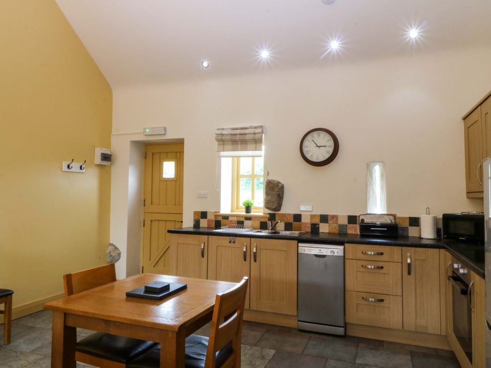A kitchen with a table and chairs at No 3 The Dairy Capel Coch near Llannerch-Y-Medd