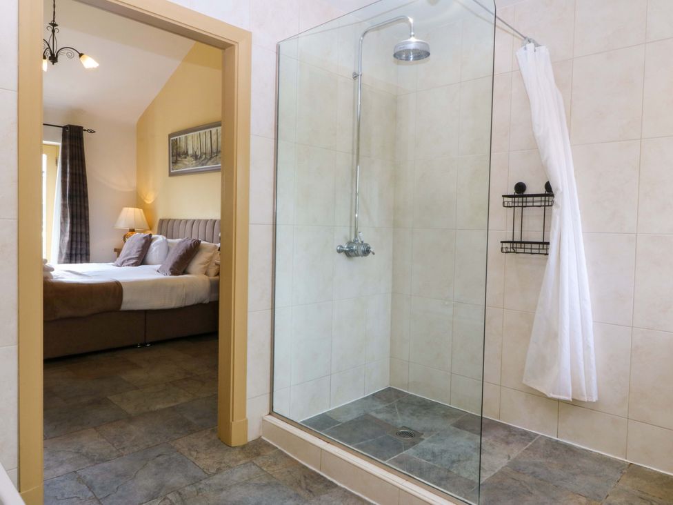 A bathroom with a shower and a view of a bedroom at No 3 The Dairy Capel Coch near Llannerch-Y-Medd