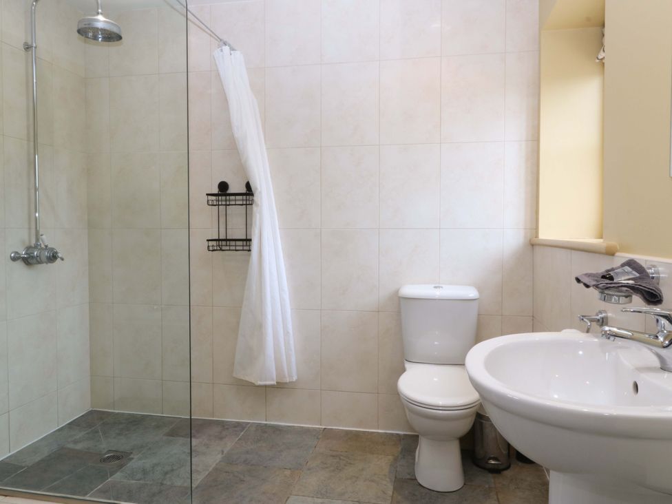 A bathroom with a shower, toilet, and sink at No 3 The Dairy Capel Coch near Llannerch-Y-Medd
