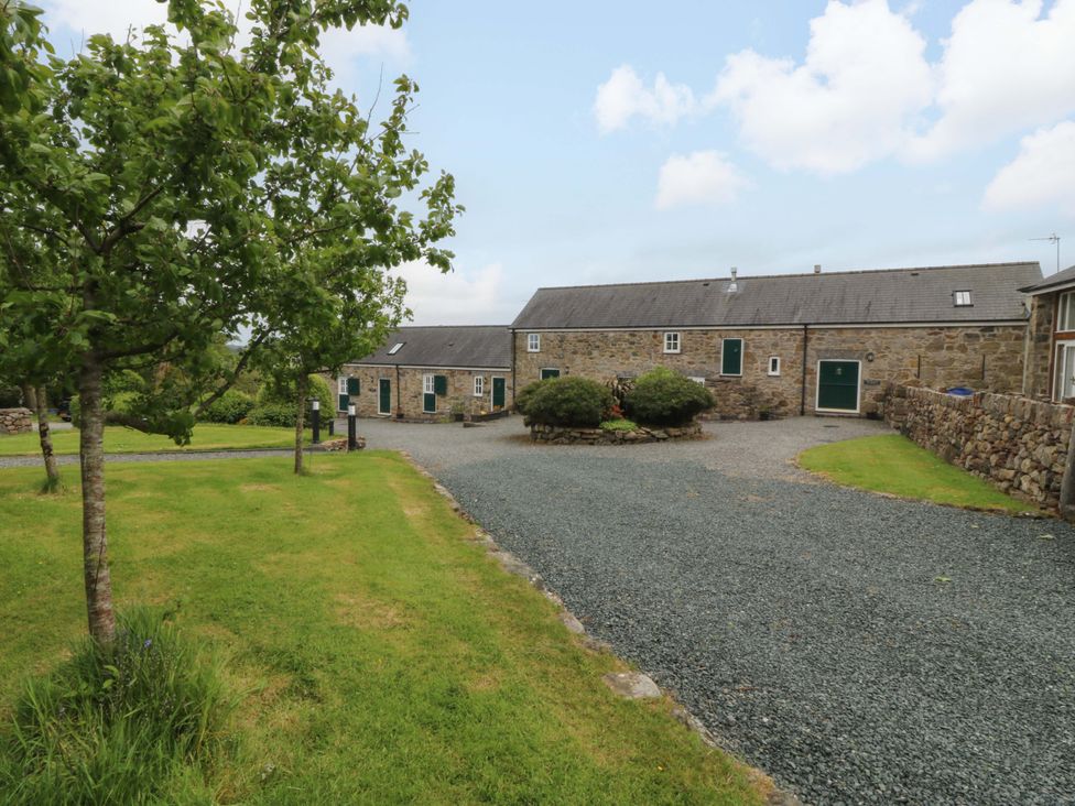 An outdoor area with stone buildings and trees at No 3 The Dairy Capel Coch near Llannerch-Y-Medd
