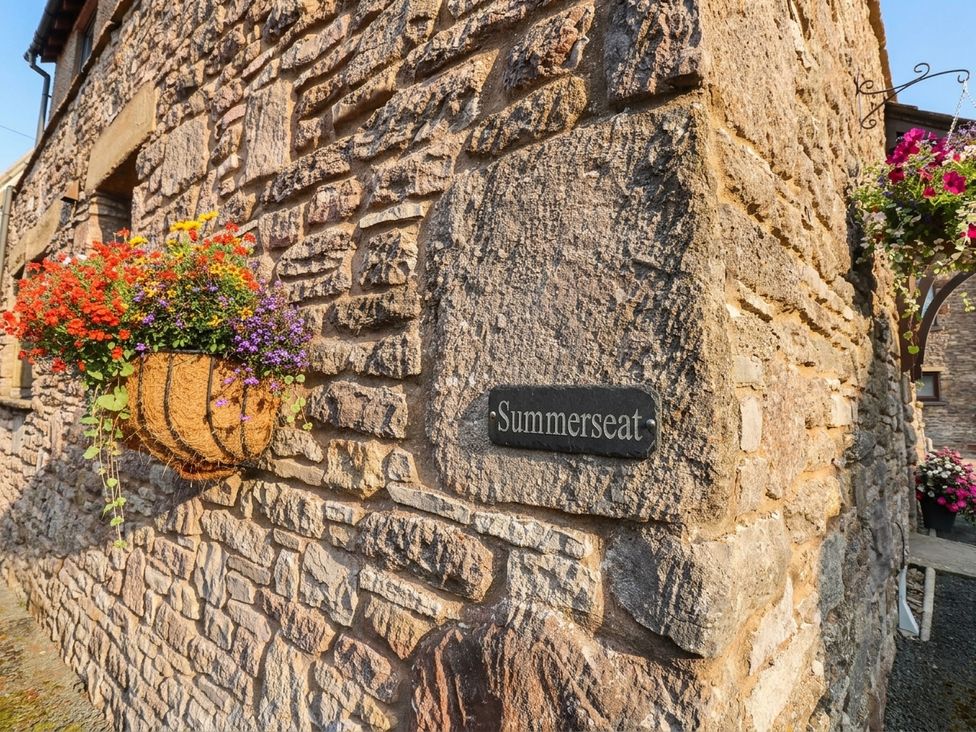 A flower basket and nameplate on a stone wall at Summerseat in Kirkby Stephen