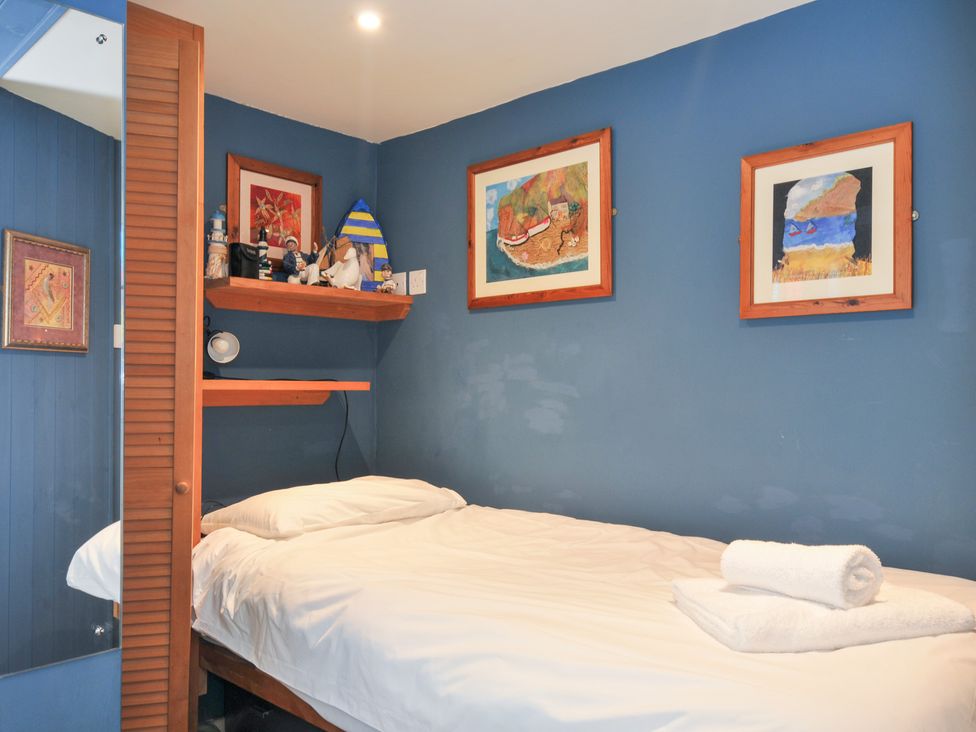 A bedroom with a bed and artwork at Beachside in Polzeath