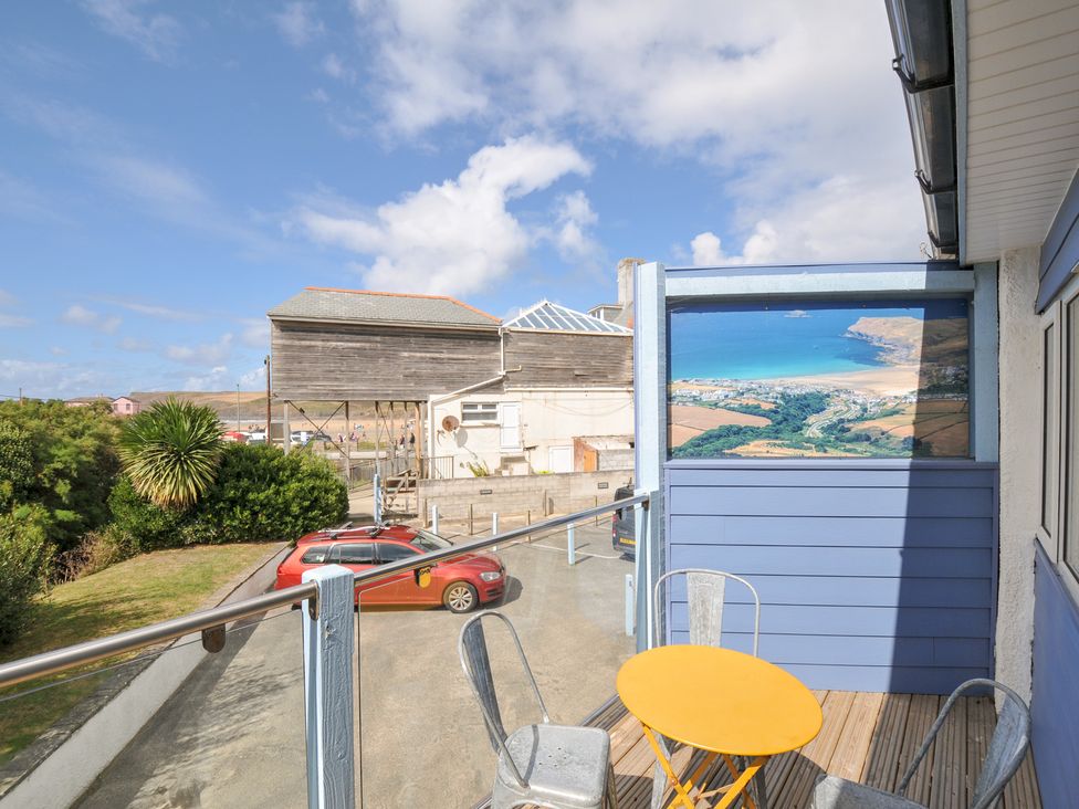A deck with a yellow table and chairs overlooking a landscape at Beachside in Polzeath