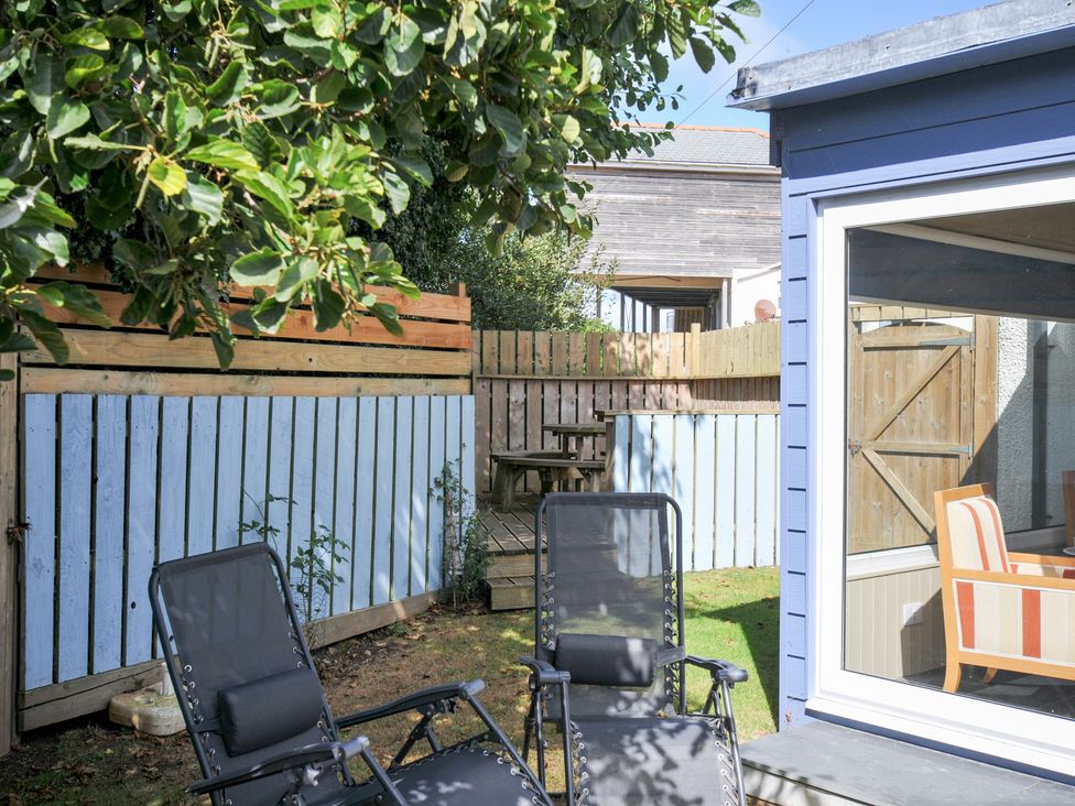 A garden area with chairs and a wooden table at Beachside in Polzeath