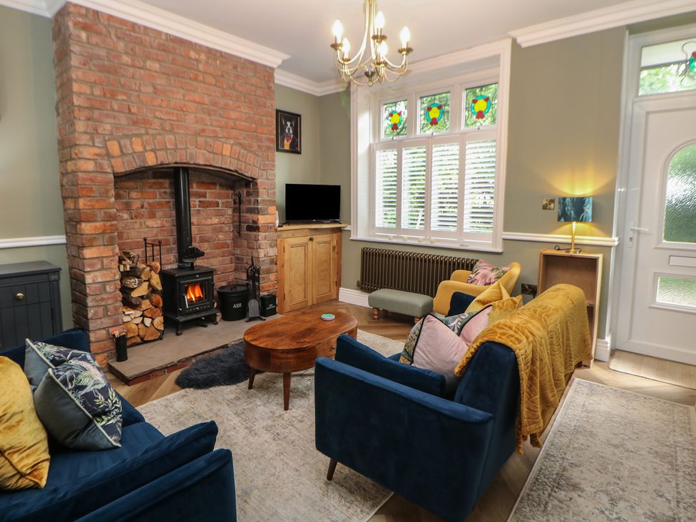 A living room with a brick fireplace and a coffee table at 16 Oak Bank in Stockport