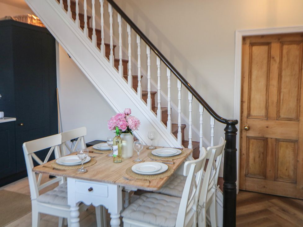A dining room with a wooden table and white chairs at 16 Oak Bank in Stockport