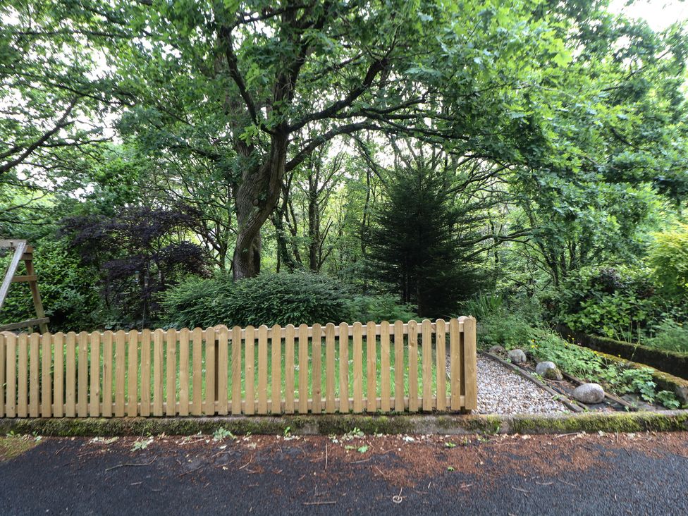 A garden with a wooden fence and trees at 16 Oak Bank Stockport