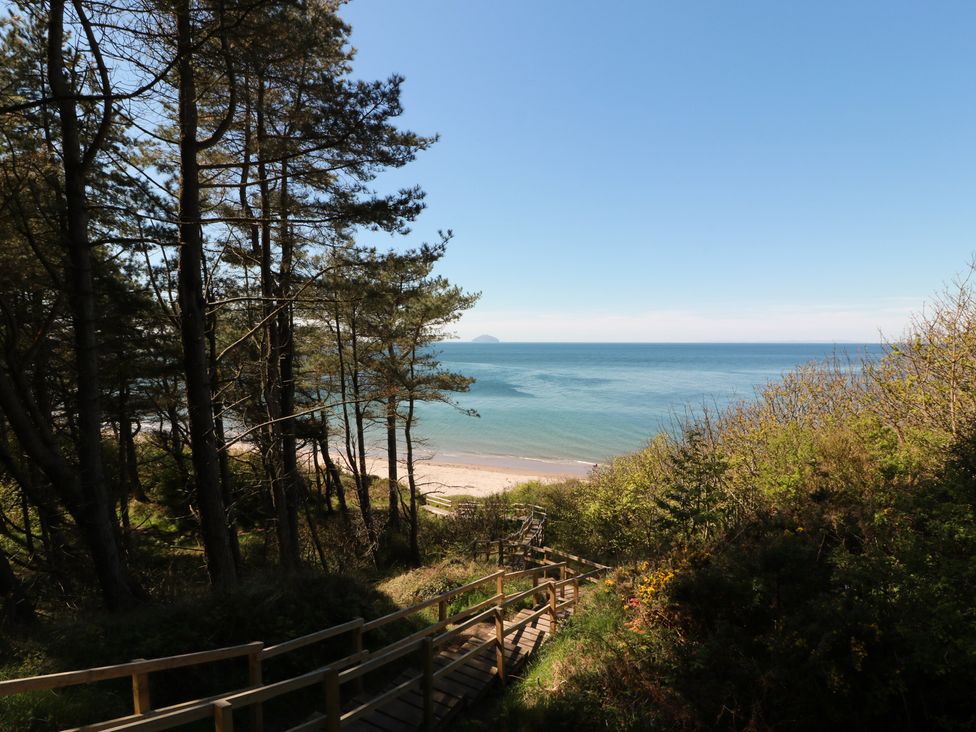 A view of the beach and ocean from a pathway surrounded by trees at Rothiemay in Maidens