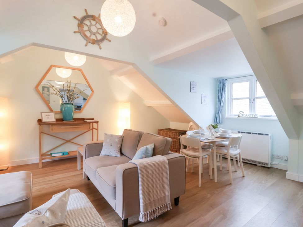 A living room with a sofa and dining table at Smugglers Loft in Looe